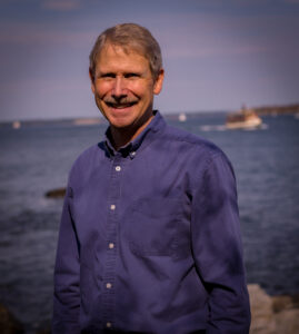 Photo of Pastor Ric in front of a boat on the water