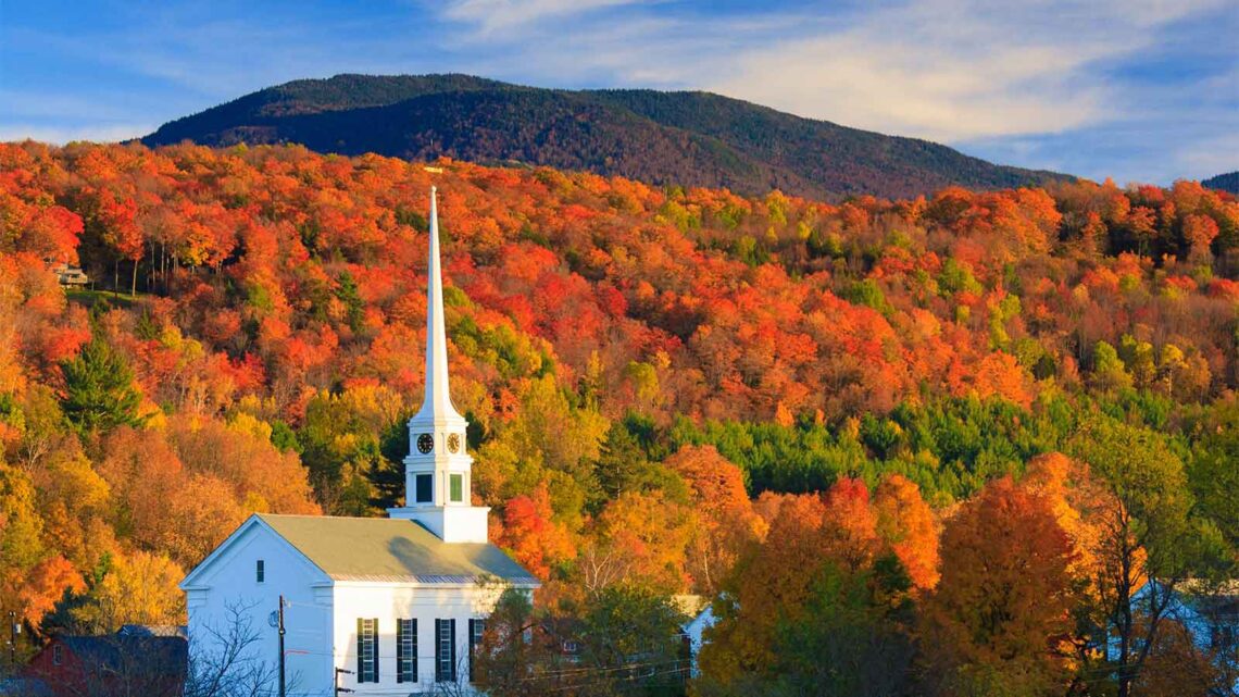 Photo of white New England church against brightly colored autumn foliage