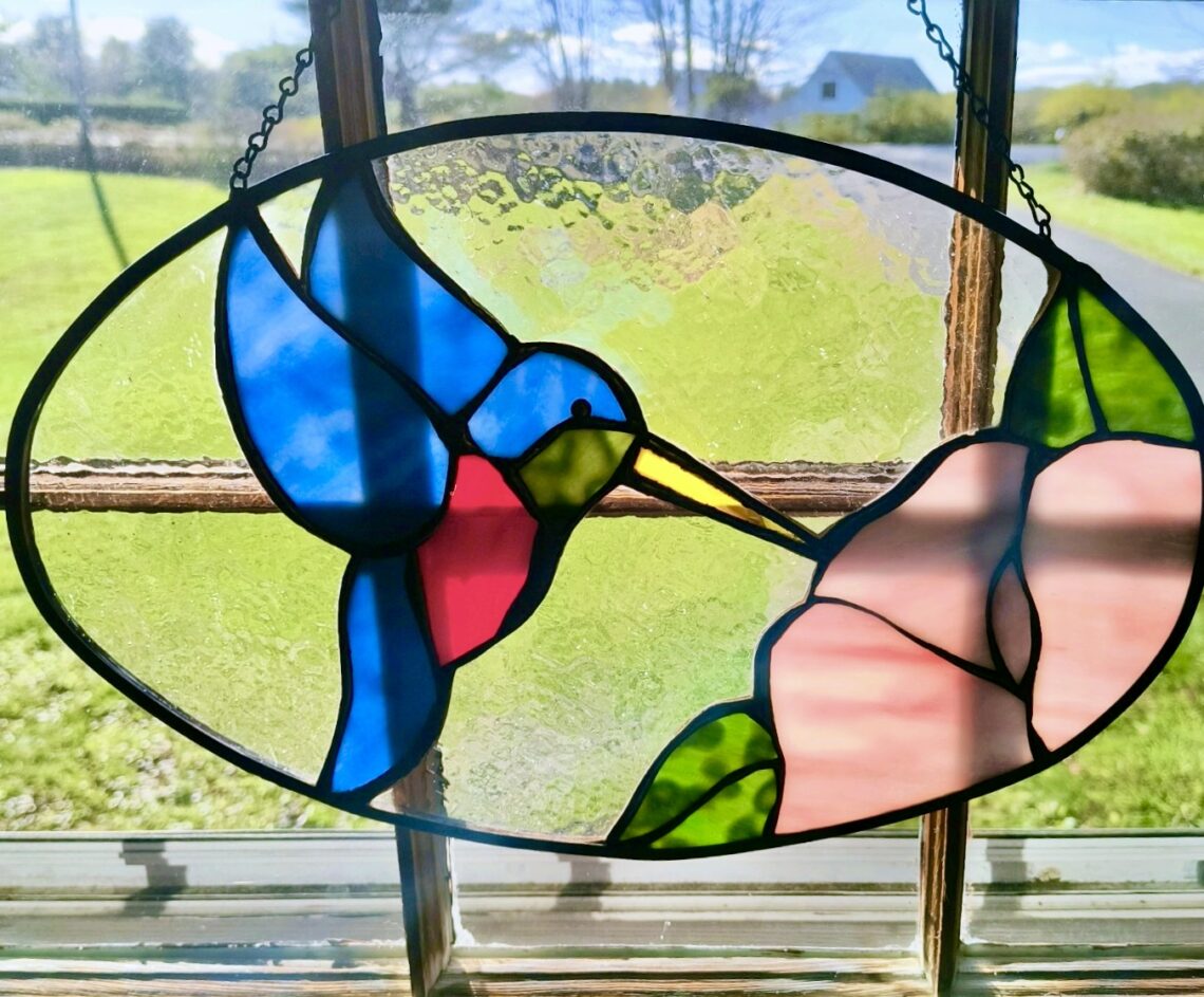 Photo of stained glass of a blue bird flying over a pink flower
