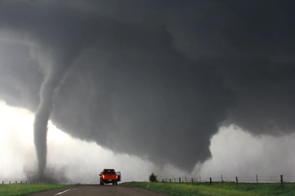 Photo of tornado next to road with red truck