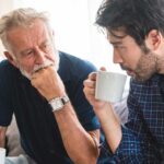 photo of an older man and a younger man sitting and talking over coffee