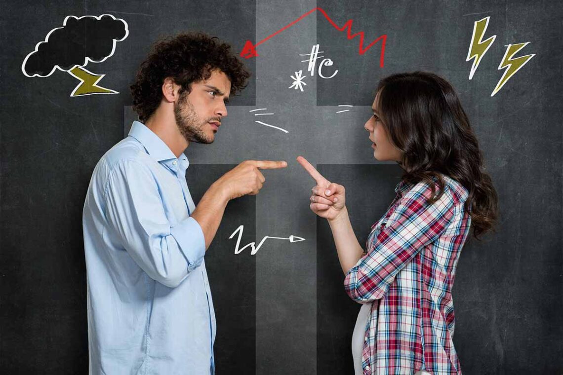 photo of a man and a woman pointing at each other in an argument against a black chalkboard background with various doodles drawn on it
