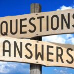 image of 2 signposts seemingly carved in wood saying Questions and Answer against a blue sky with a couple clouds